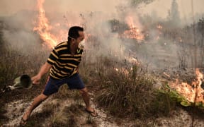 A villager tries to extinguish a peatland fire on the outskirts of Palangkaraya city, Central Kalimantan on October 26, 2015. For nearly two months, thousands of fires caused by slash-and-burn farming in Indonesia choked vast expanses of Southeast Asia.