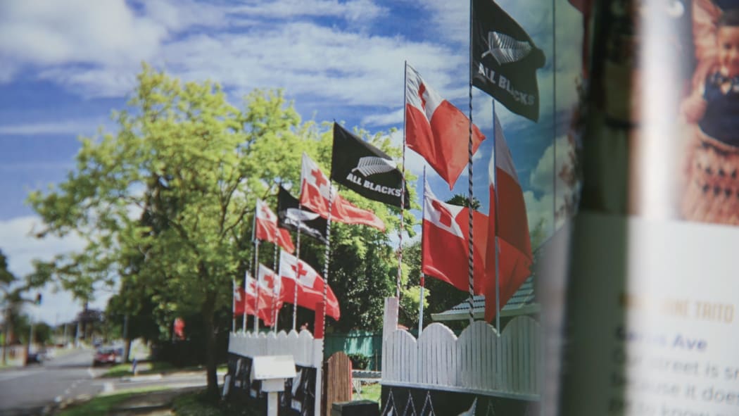 A picture of Tongan and All Blacks flags flying on a street in Māngere from the book Where I Live.
