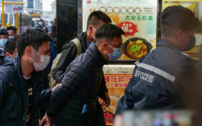 Stand News chief editor Patrick Lam (C) is brought to the news outlet's office building in handcuffs after police were deployed to search the premises in Hong Kong's Kwun Tong district on 29 December 2021.