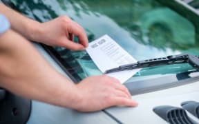 Man finding a ticket fine under the car windscreen because of parking violation