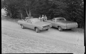 People talking next to two Ford Falcon utes (pick up truck),