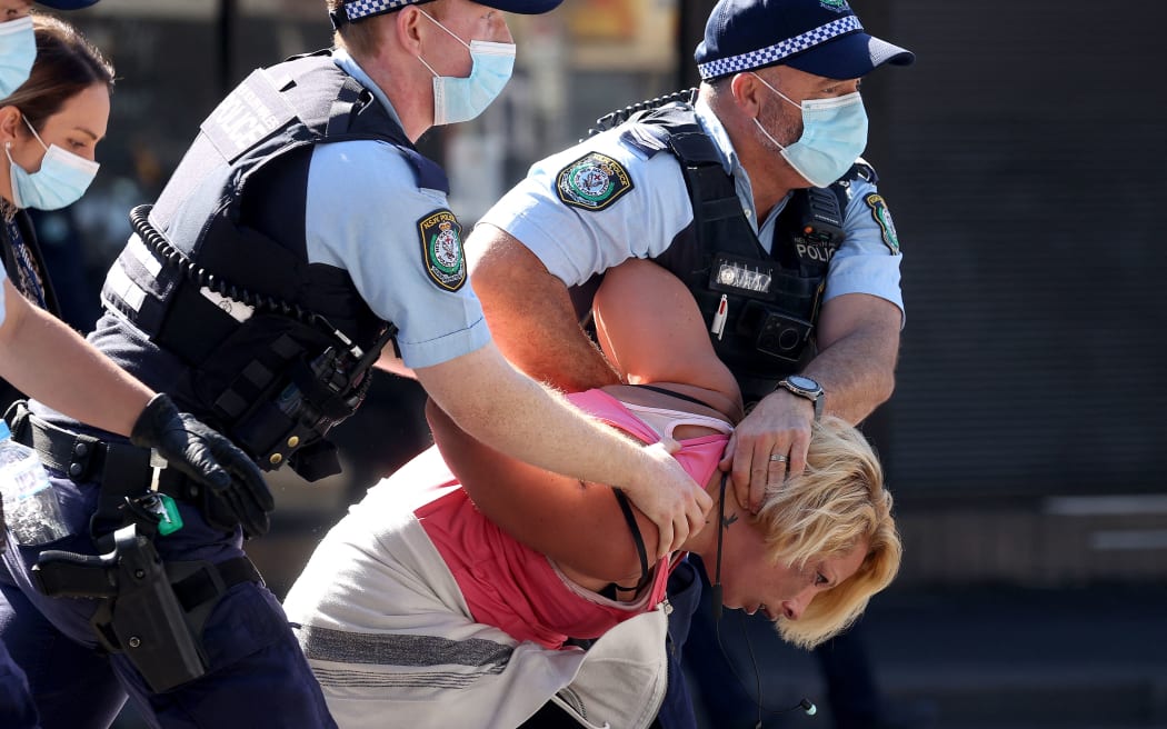 Police officers detain an anti-lockdown protester in Sydney.