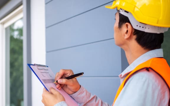 The inspector or engineer is checking the building structure and the requirements of the wall paint.