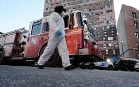 A clean-up and recovery worker walks in front of a Bronx apartment building a day after a fire swept through the complex killing at least 17 people.