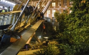 A protester lowers herself down a rope from a bridge to a highway, to escape from Hong Kong Polytechnic University campus and from police