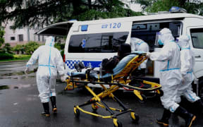 Medical workers of the medical emergency center of Minhang District of Shanghai transfer a patient onto an ambulance in Shanghai, east China, April 23, 2022.