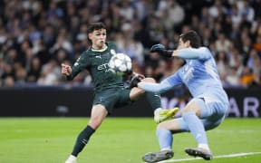 Thibaut Courtois of Real Madrid (R) and Phil Foden of Manchester City in action during a 2025 Champions League match.