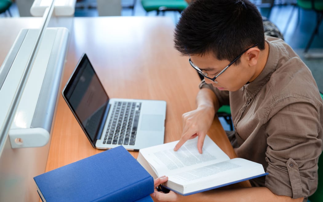 Portrait of asian male student reading book in university