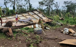A child standing on top of what is left of a house structure following Cyclone Judy.