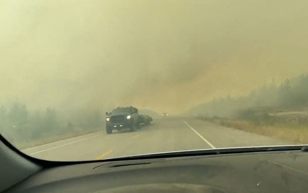 This screengrab from a video provided by Jordan Straker shows vehicles driving on the freeway as people evacuate from Yellowkife, Northwest Territories, Canada, on August 16, 2023. Thousands ordered to flee wildfires advancing on one of the largest cities in Canada's far north crammed into a local airport on August 17, 2023, to board emergency evacuation flights, as convoys snaked south to safety on the only open highway.