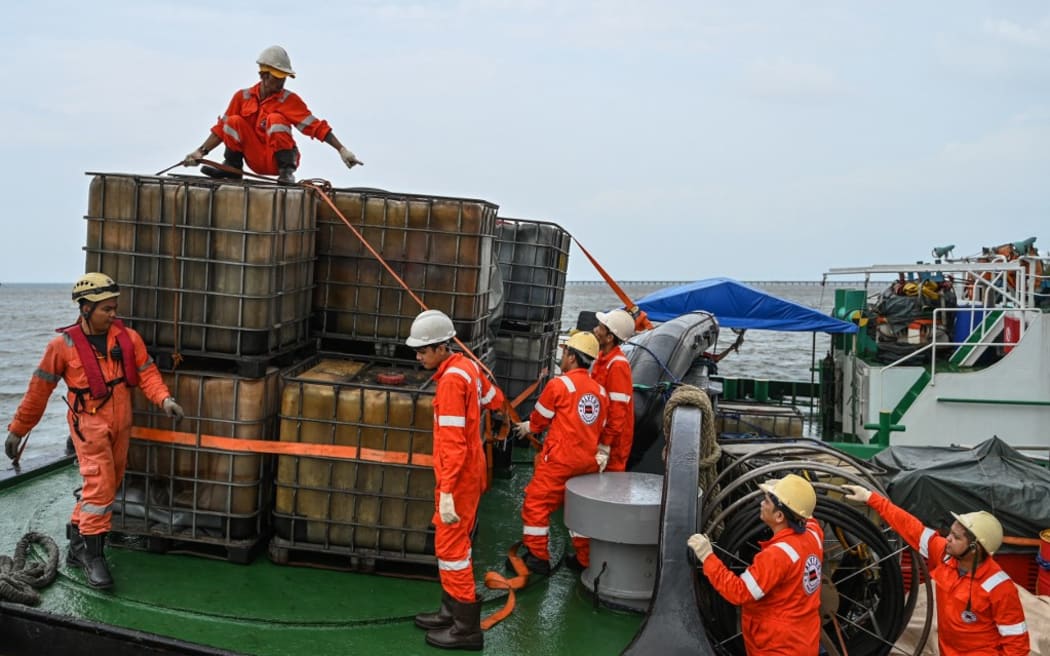 Crew of a private company secure containers to be used in the oil spill response, at a port in Limay, Bataan on July 26, 2024. A Philippine-flagged tanker carrying 1.4 million litres of industrial fuel oil capsized and sank off Manila on July 25, authorities said, as they raced against time to contain the spill. (Photo by Jam Sta Rosa / AFP)