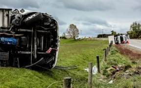 Two refrigerated trucks lay on their sides after toppling on an exposed part of SH1 just outside of Balclutha