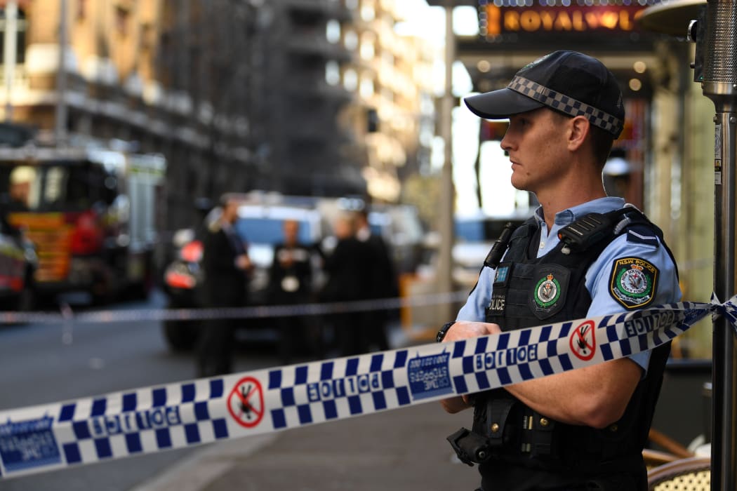 A policeman stands by a roped off crime scene after a man stabbed a woman and attempted to stab others in central Sydney.