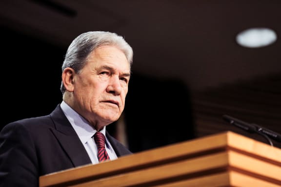 Winston Peters standing in the Beehive Theatre, making an announcement.