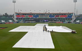 Groundsmen cover the pitch as it rains before the start of the ICC Champions Trophy match between Australia and South Africa in Rawalpindi, 2025.