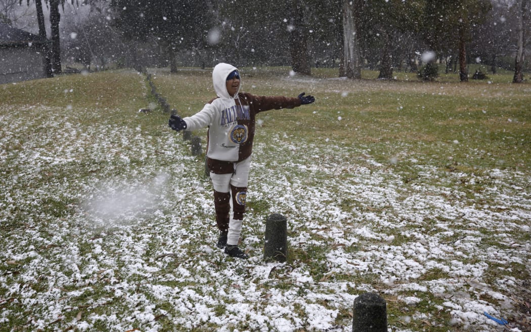 Gabriel Sussman gestures as snow falls in Zoo Lake park in Johannesburg on 10 July 2023.