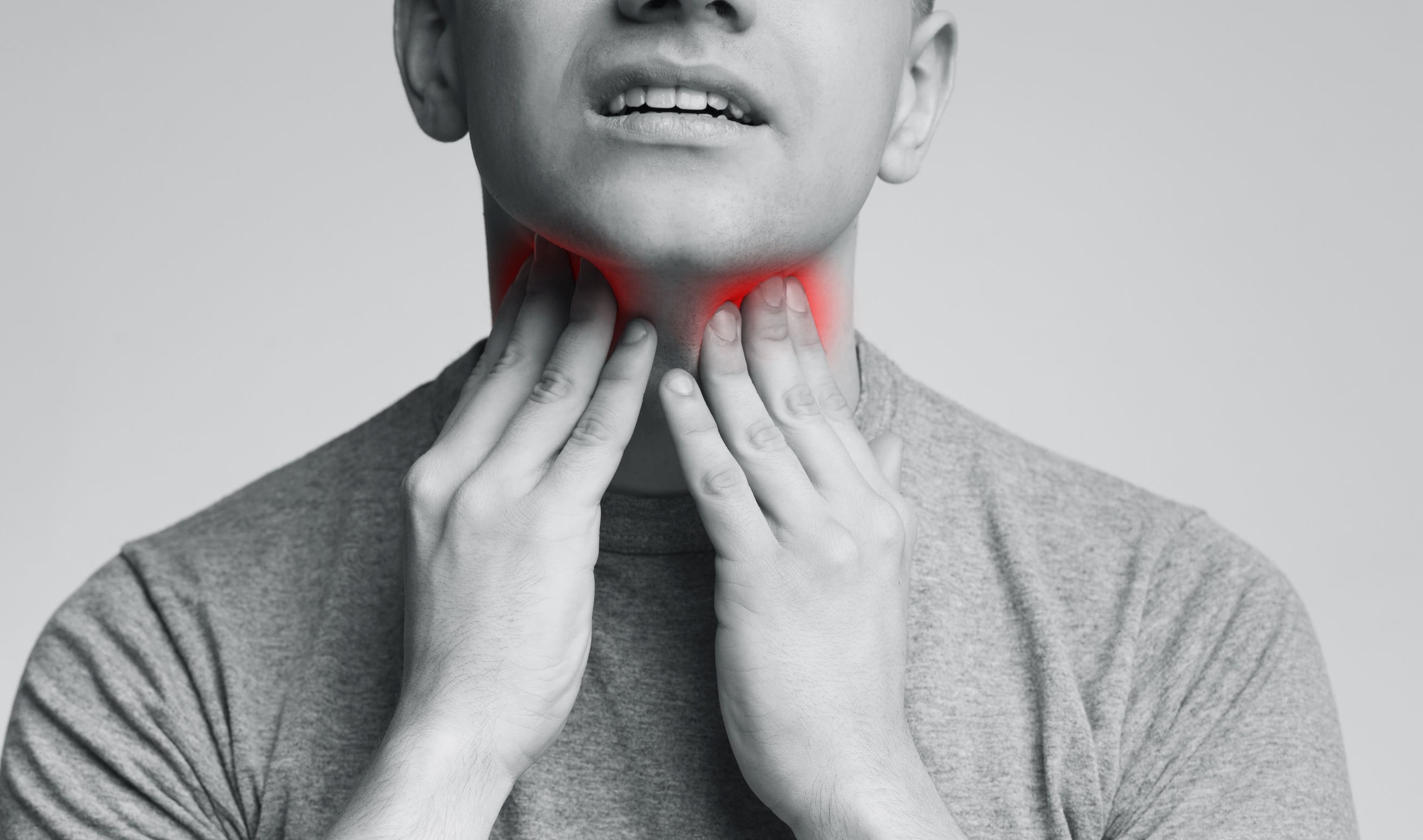 Man with thyroid gland problem, touching his neck.