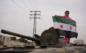 Celebrations in the city of Hama, where Syrians gather at Al-Assi Square to take commemorative photos and express their joy over the city's control. The square is filled with the sounds of celebratory gunfire and the distribution of sweets to mark the occasion.