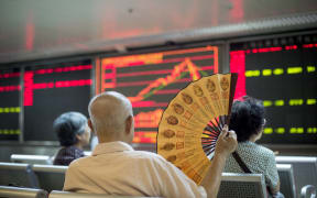 Investors look at screens showing stock market movements at a securities company in Beijing.