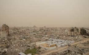 A haze of dust hangs over the Tel al-Hawa neighbourhood of Gaza City during a severe storm on February 13, 2026. Strong winds carry thick dust across the city, blanketing tents sheltering displaced Palestinians and compounding already harsh living conditions in areas heavily damaged during war. (Photo by Hassan Salem / Middle East Images via AFP)