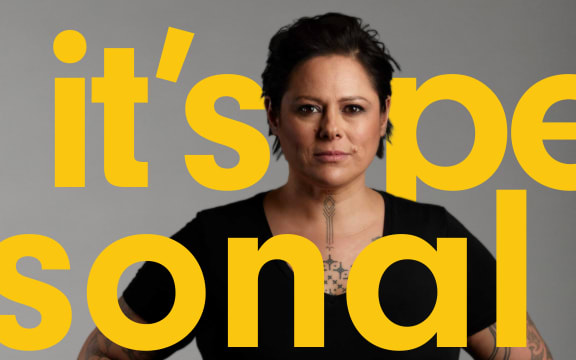 Photo of Anika Moa in black with hands on hips, looking straight ahead to camera, on a light grey background. The podcast title ‘Its Personal’ Is written in bright yellow in front and behind her.
