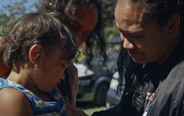 A long-haired woman is emotional as she looks at a young boy who is averting his eyes.