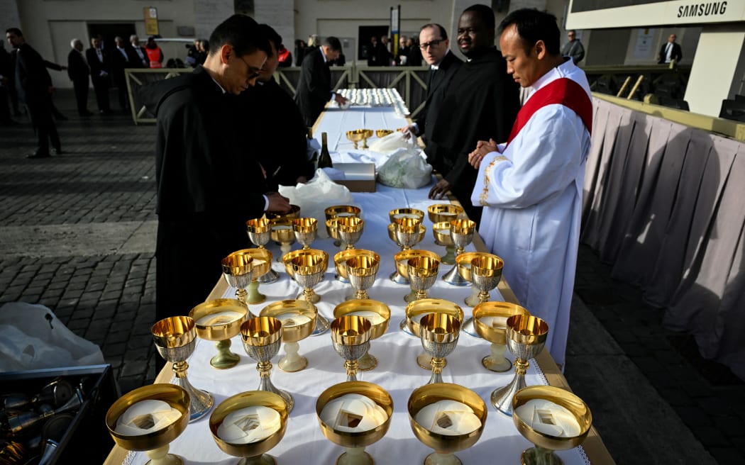 Priests prepare the hosts ahead of the start of late Pope Francis' funeral ceremony in St Peter's Square at the Vatican on April 26, 2025. (Photo by Alberto PIZZOLI / AFP)
