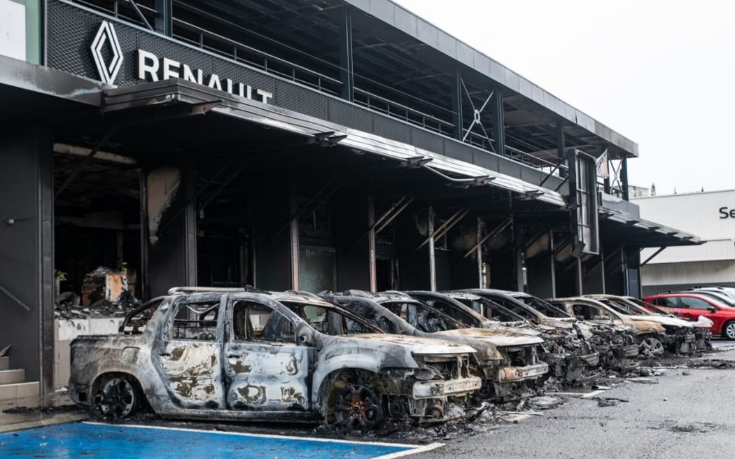 Cette photo montre des voitures incendiées sur un parking Renault Dacia du quartier Magenta de Nouméa, territoire français du Pacifique de Nouvelle-Calédonie, le 17 mai 2024. La France a envoyé des troupes dans les ports et l'aéroport international de Nouvelle-Calédonie, a interdit TikTok et a imposé l'état d'urgence le 16 mai, après trois nuits d'affrontements qui ont fait quatre morts et des centaines de blessés. Les manifestations, largement nationales, contre un projet français visant à imposer de nouvelles règles de vote à ce pays insulaire du Pacifique indépendantiste se sont transformées en violences les plus meurtrières depuis les années 1980, avec un policier tué dans une fusillade. (Photo de Delphine Mayeur / AFP)