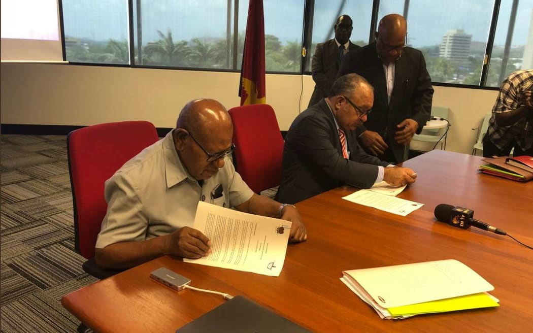 Bougainville president John Momis, left, and former PNG Prime Minister Peter O'Neill sign the agreement on the question for the independence referendum.