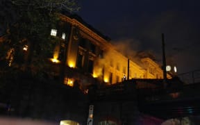 Smoke billows out of Sydney's Central Railway Station, lit by yellow lights.