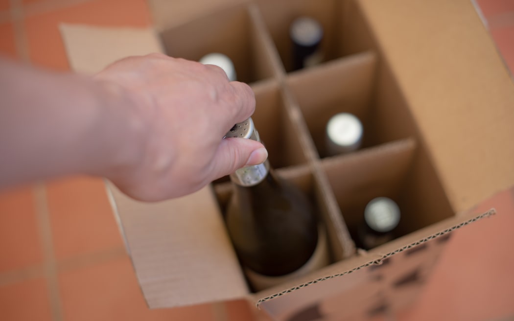 Person taking wine bottle out of box.