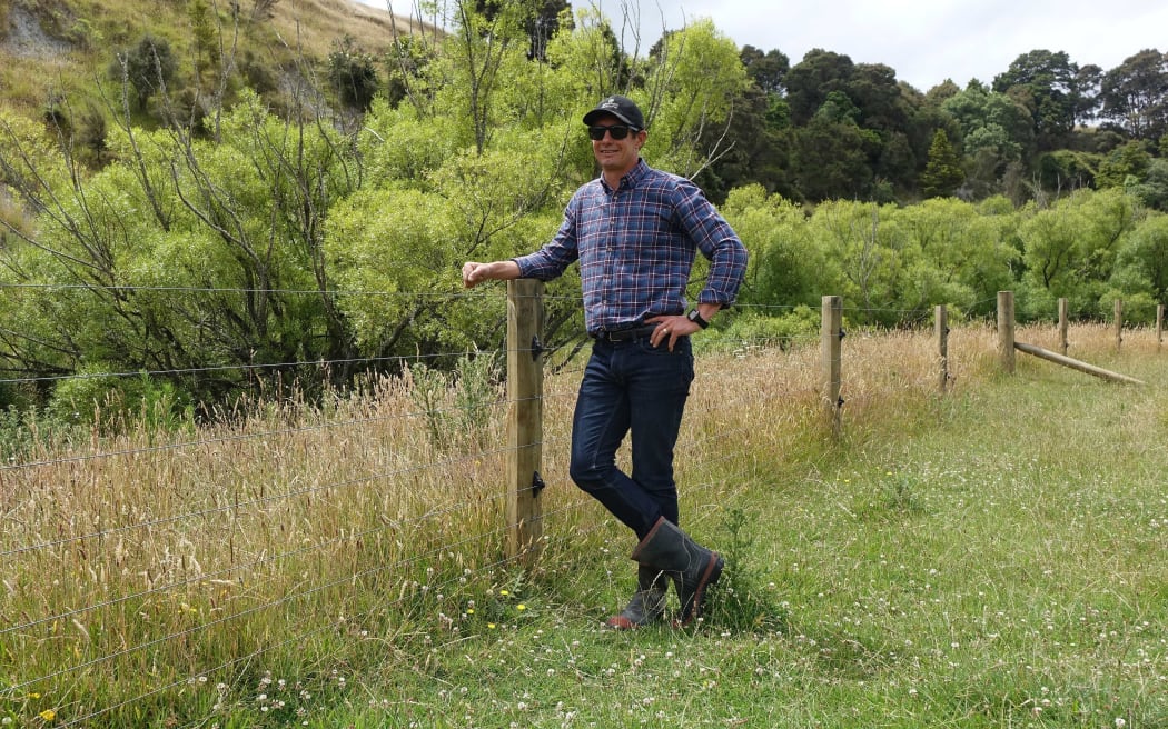 Yong farmer in cap stands by new fence r