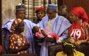 Nigerian President Mohammadu Buhari holds the daughter of Amina Ali Nkeki.