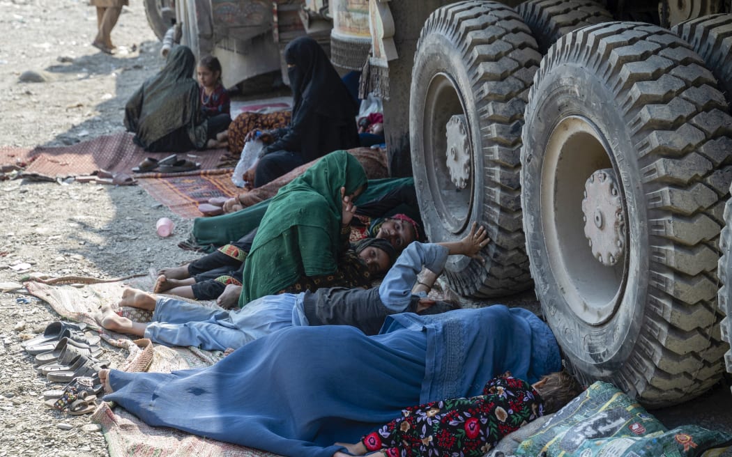 Afghan refugees rest beside a truck on their arrival from Pakistan at the Afghanistan-Pakistan Torkham border in Nangarhar province on 30 October, 2023. Islamabad has issued an order to 1.7 million Afghans it says are living in the country illegally to leave by 1 November, or be deported.