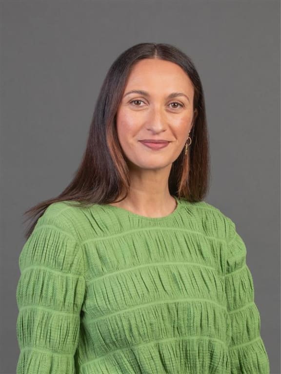 A Māori woman with long hair and a green top