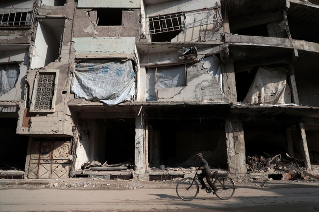 A Syrian boy cycles past damaged buildings in the rebel-held town of Douma, on 30 December 2016, on the first day of a nationwide truce.