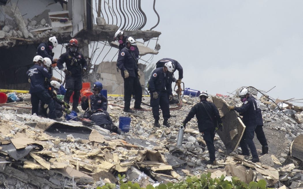 Members of the South Florida Urban Search and Rescue team look for possible survivors in the partially collapsed 12-story Champlain Towers South condo building on 26 June 2021 in Surfside, Florida.