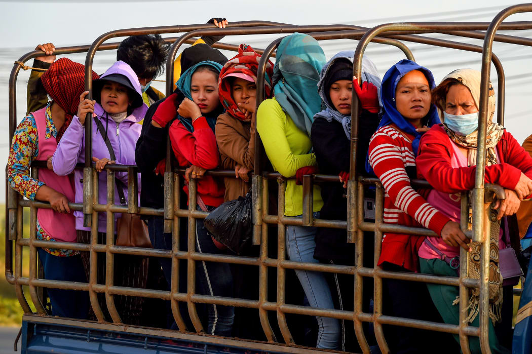 garment factory workers standing in a truck, which they use to commute to and from work, in Kampong Speu province, Cambodia.