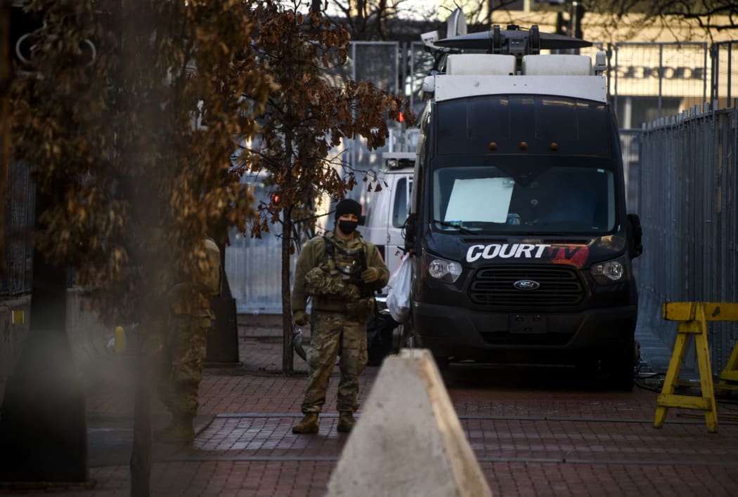 A Court TV vehicle parked outside the Hennepin County Government Center and a member of the National Guard looks on while jury selection in the trial for Derek Chauvin is underway inside.