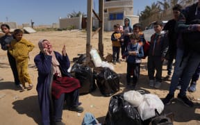 A woman who fled with others the Al-Shifa hospital and its vicinity in Gaza City reacts as she sits amid some of her belongings in central Gaza, on March 21, 2024. Israel's army was on March 21 four days into a raid at Al-Shifa, Gaza's largest hospital, where the military says Hamas was operating from among patients and displaced civilians. (Photo by AFP)