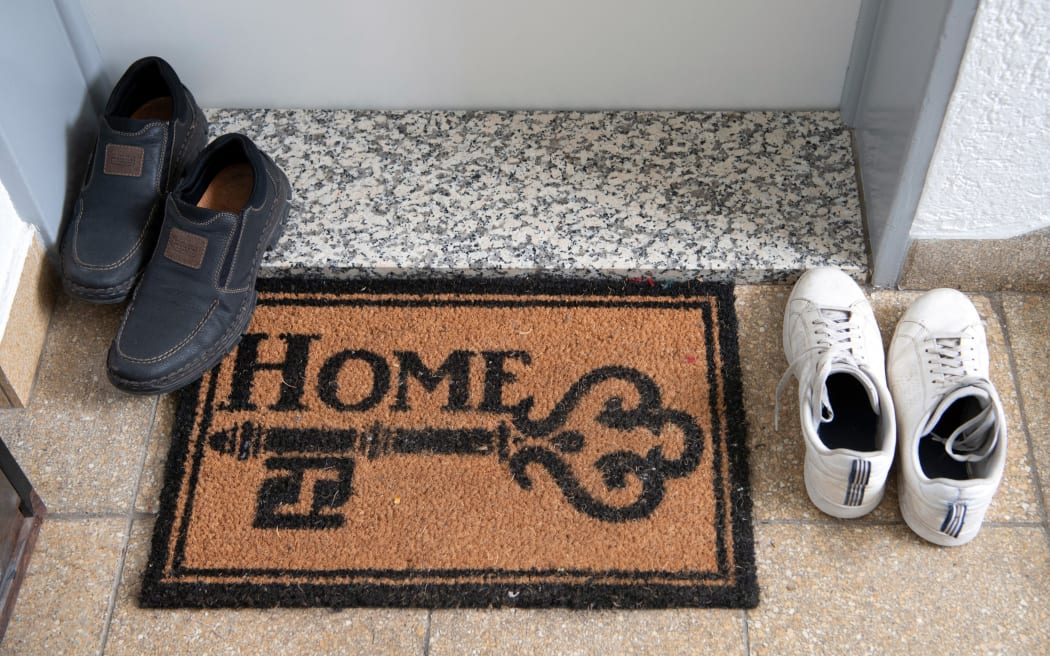 27 May 2019, Hessen, Frankfurt/Main: Two pairs of shoes stand next to a doormat with the inscription "Home". The installation of modular living elements on the upper floors of existing buildings is intended to create more living space in Frankfurt. (Too much focus from 27.05.2019) Photo: Boris Roessler/dpa (Photo by BORIS ROESSLER / DPA / dpa Picture-Alliance via AFP)