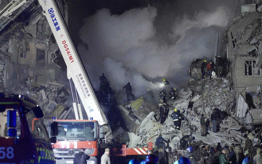 Rescuers work on a residential building destroyed after a missile strike, in Dnipro on January 14, 2023. - A strike on a residential building in the eastern Ukrainian city of Dnipro on January 14, 2023 killed at least five people and wounded 39, officials said, as the president blasted Russian "terror".