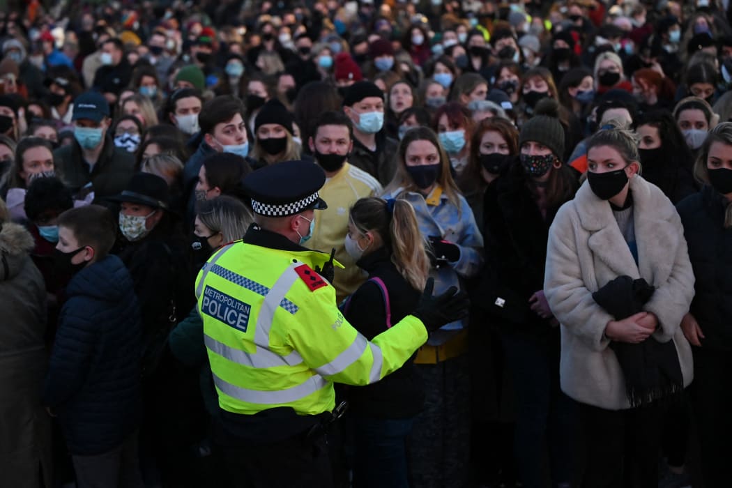 A police officer asks well-wishers not to linger and to move on as they gather at the band-stand where a planned vigil in honour of murder victim Sarah Everard, which was officially cancelled due to Covid-19 restrictions, was to take place on Clapham Common, south London on 13 March 2021.