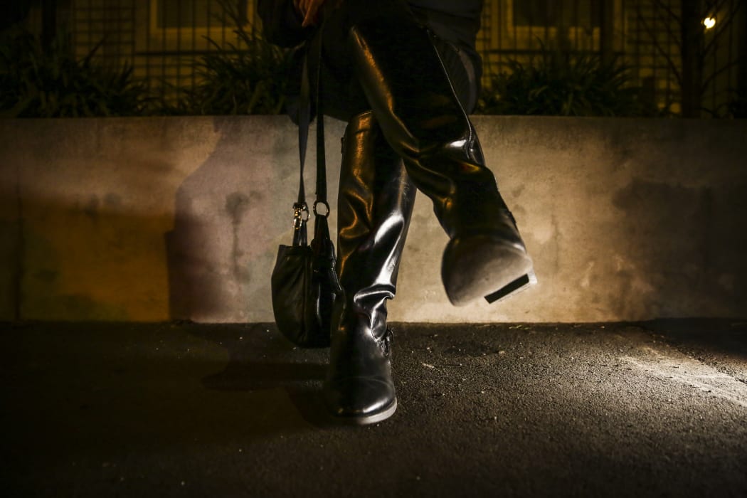 Photo of  a woman's long winter boots as she sits on a wall