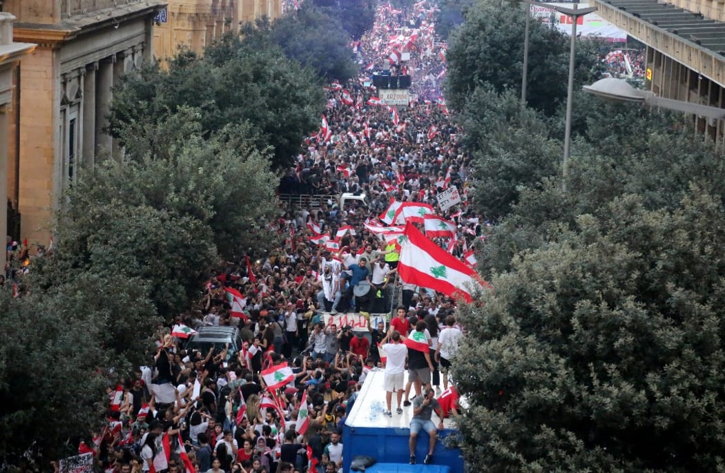 Thousands of Lebanese demonstrators wave their country's flag during a mass protest in Beirut demanding the fall of the government.