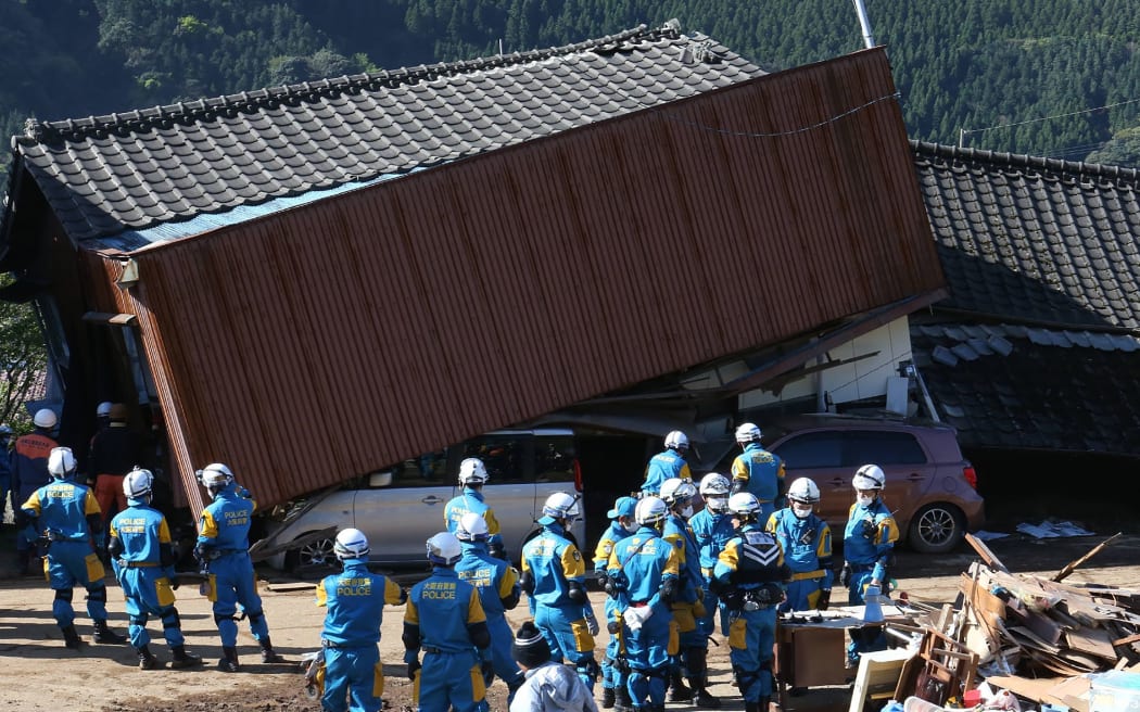 Rescue workers try to save people from a collaspsed house in Mimami-Aso, Kuammoto prefecture in Japan following another large earthquake in days.