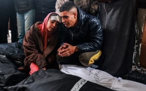 An injured girl and man mourn over the bodies of relatives killed in overnight Israeli bombardment, at the Al-Najjar hospital in Rafah in the southern Gaza Strip on February 23, 2024, as battles between Israel and the Palestinian militant group Hamas continue.