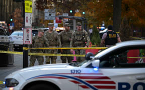 National Guard soldiers stand behind the crime scene tape after a shooting in downtown Washington, DC, on November 26, 2025. Metropolitan Police in Washington said Wednesday they had detained a suspect after two National Guard troops were shot blocks away from the White House. (Photo by Drew ANGERER / AFP)