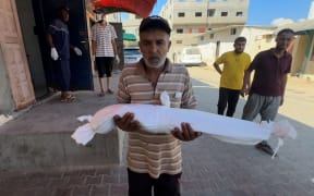 Razan Abu Zaher’s shrouded body is carried after she died from malnutrition.