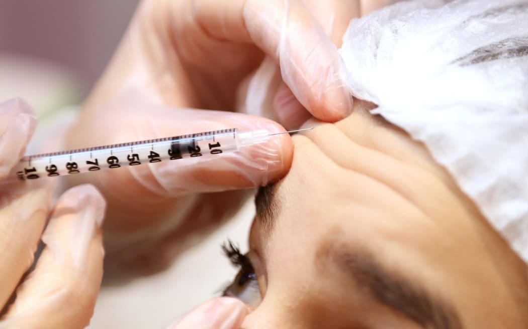 A woman receives an injection to the forehead